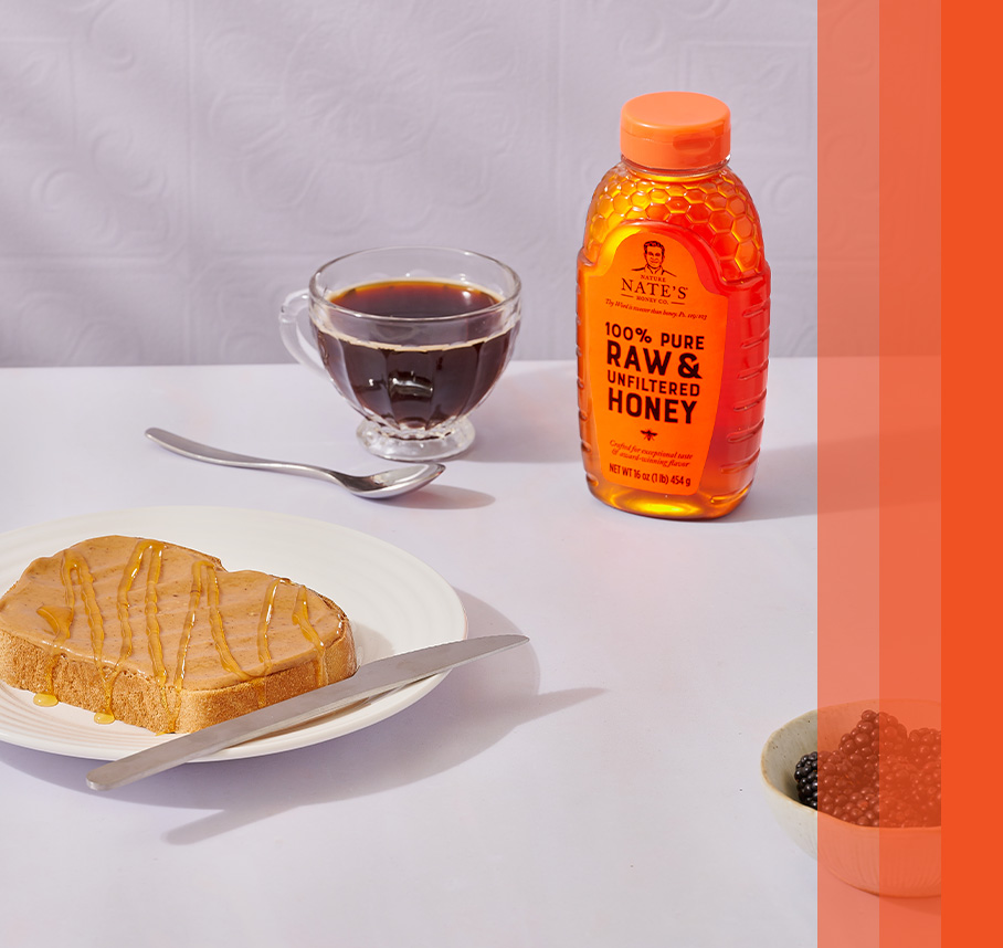 Peanut butter and honey toast on a plate with a bottle of Nature Nate's Honey in the background on a white table.