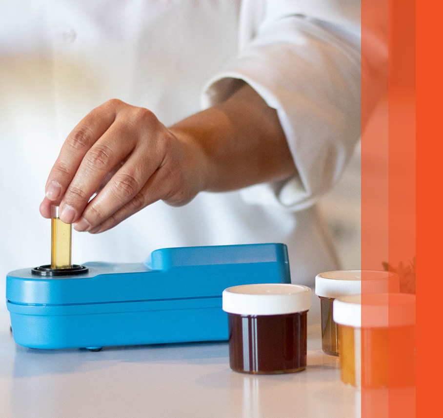 Lab worker testing honey with orange bars on right.